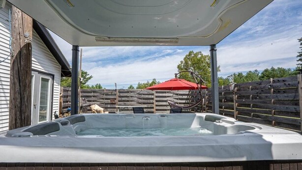 Un jacuzzi con un muelle de madera y una sombrilla roja al fondo.