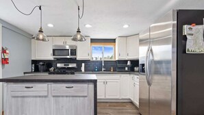 Una cocina moderna con armarios blancos, electrodomésticos de acero inoxidable e iluminación colgante.