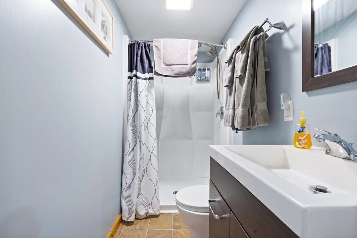 Een badkamer met douche, toilet en wastafel.
