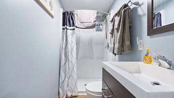 Een badkamer met douche, toilet en wastafel.