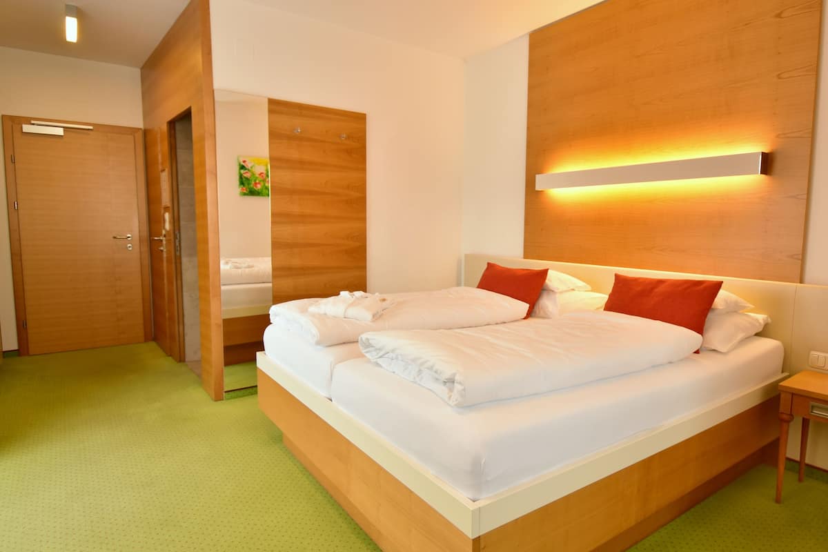 Een moderne hotelkamer met een groot bed, een houten hoofdbord en een groen tapijt.