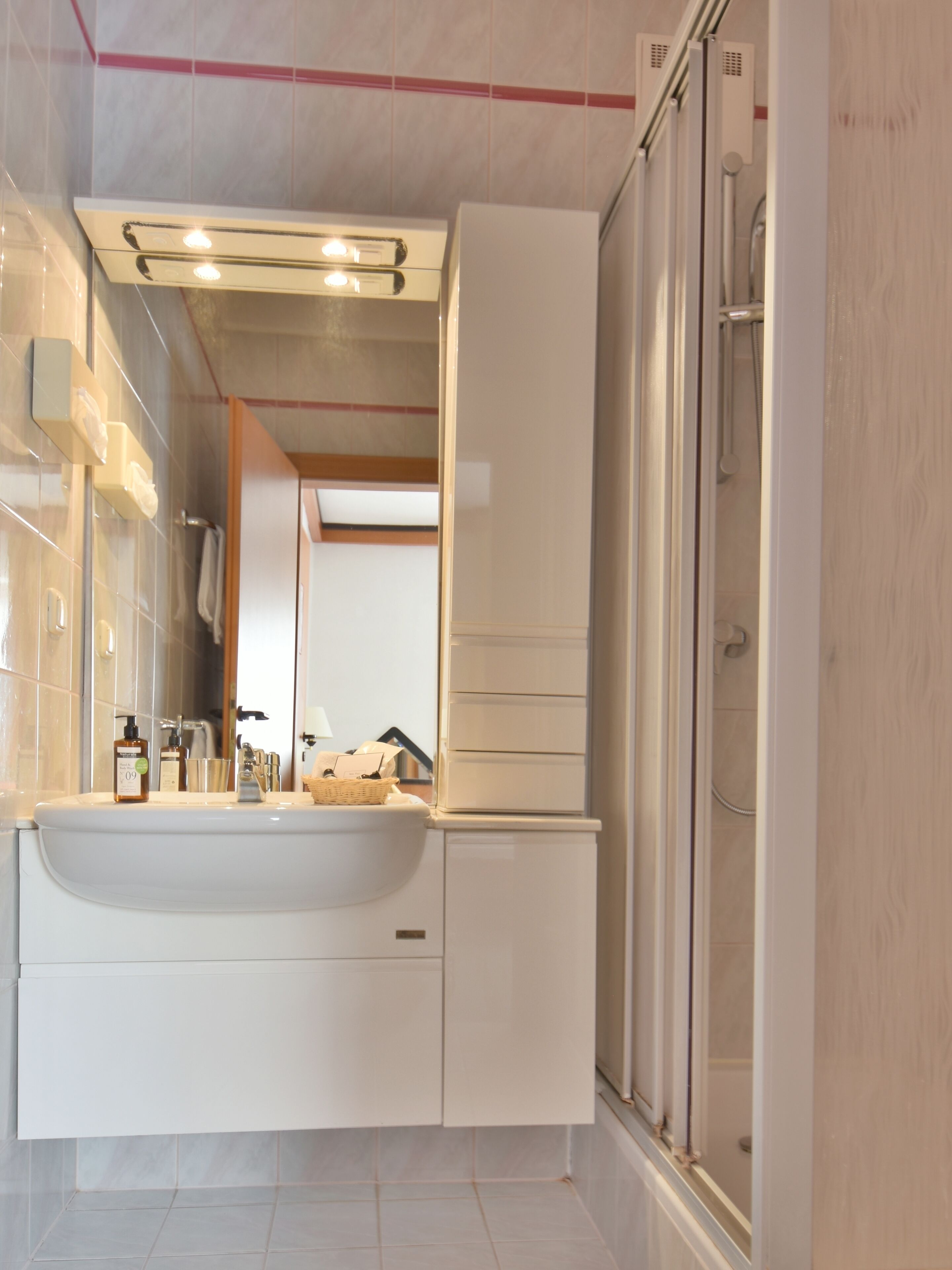 A modern bathroom with a large sink, mirror, and shower.