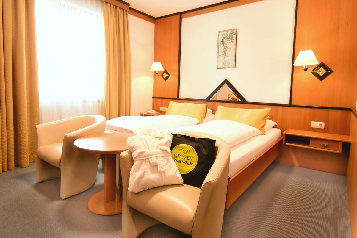 Een hotelkamer met een bed, een stoel, een klein tafeltje en een nachtkastje.