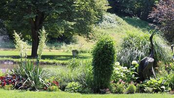 A garden with a fountain, various plants, and a statue.