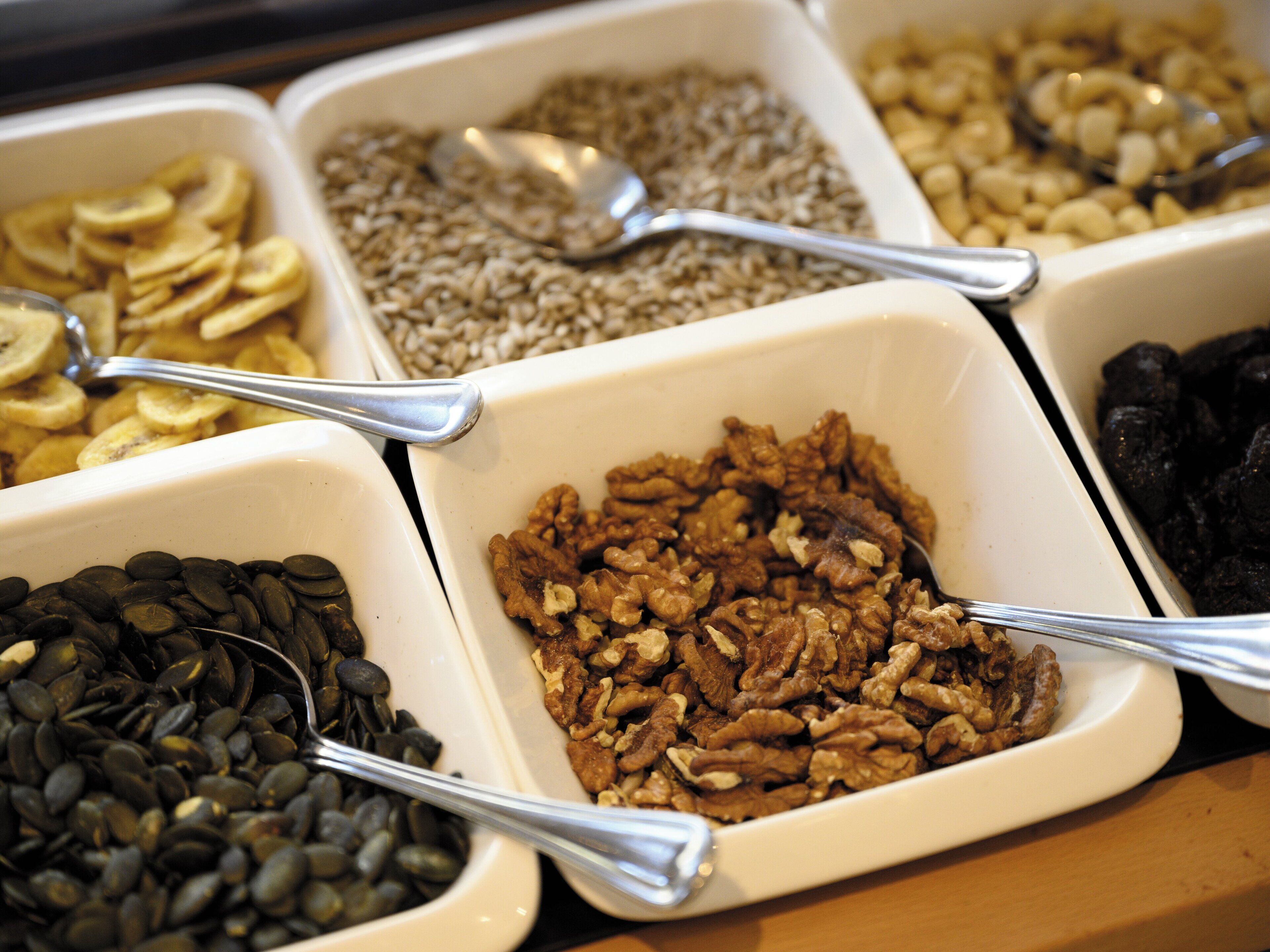 A variety of food items in white bowls with spoons.