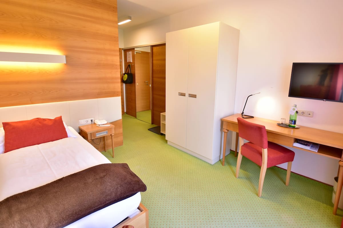 Een hotelkamer met een bed, bureau, stoel, televisie en kledingkast.