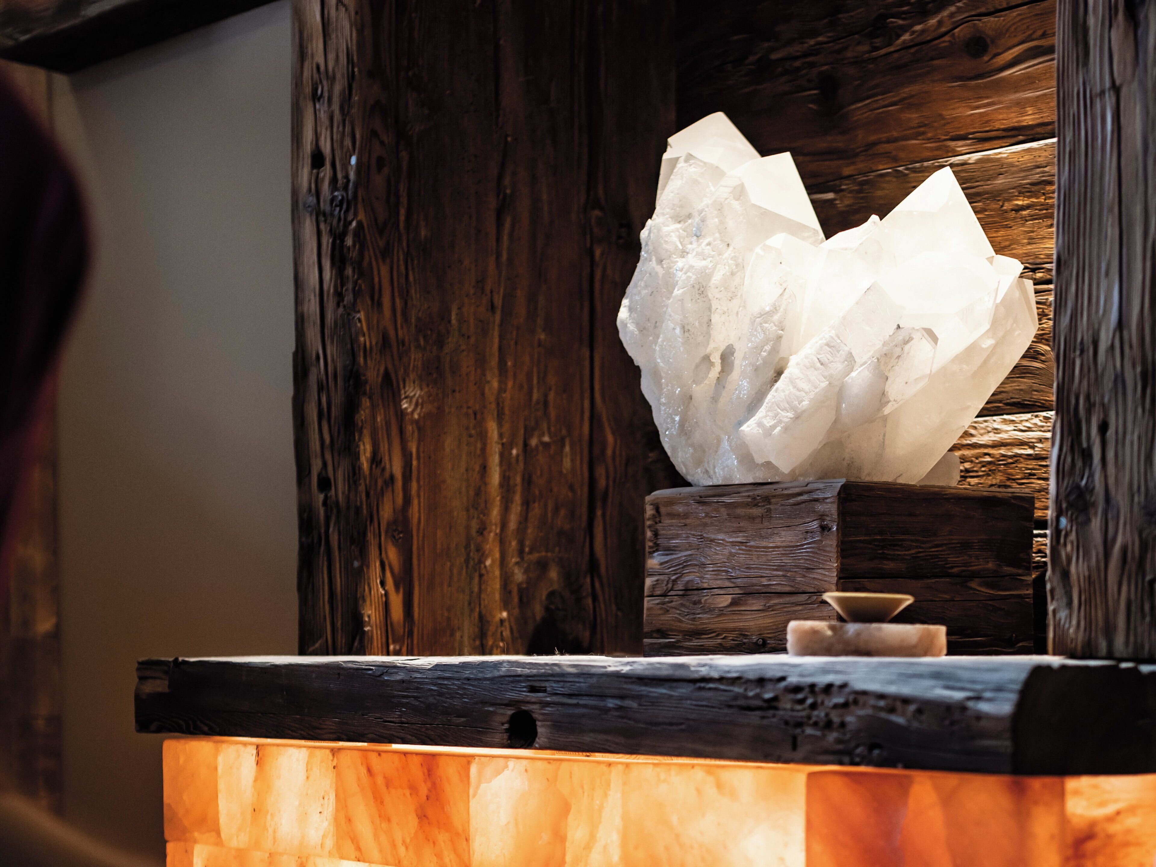 A large white crystal on a wooden block, set against a wooden wall.