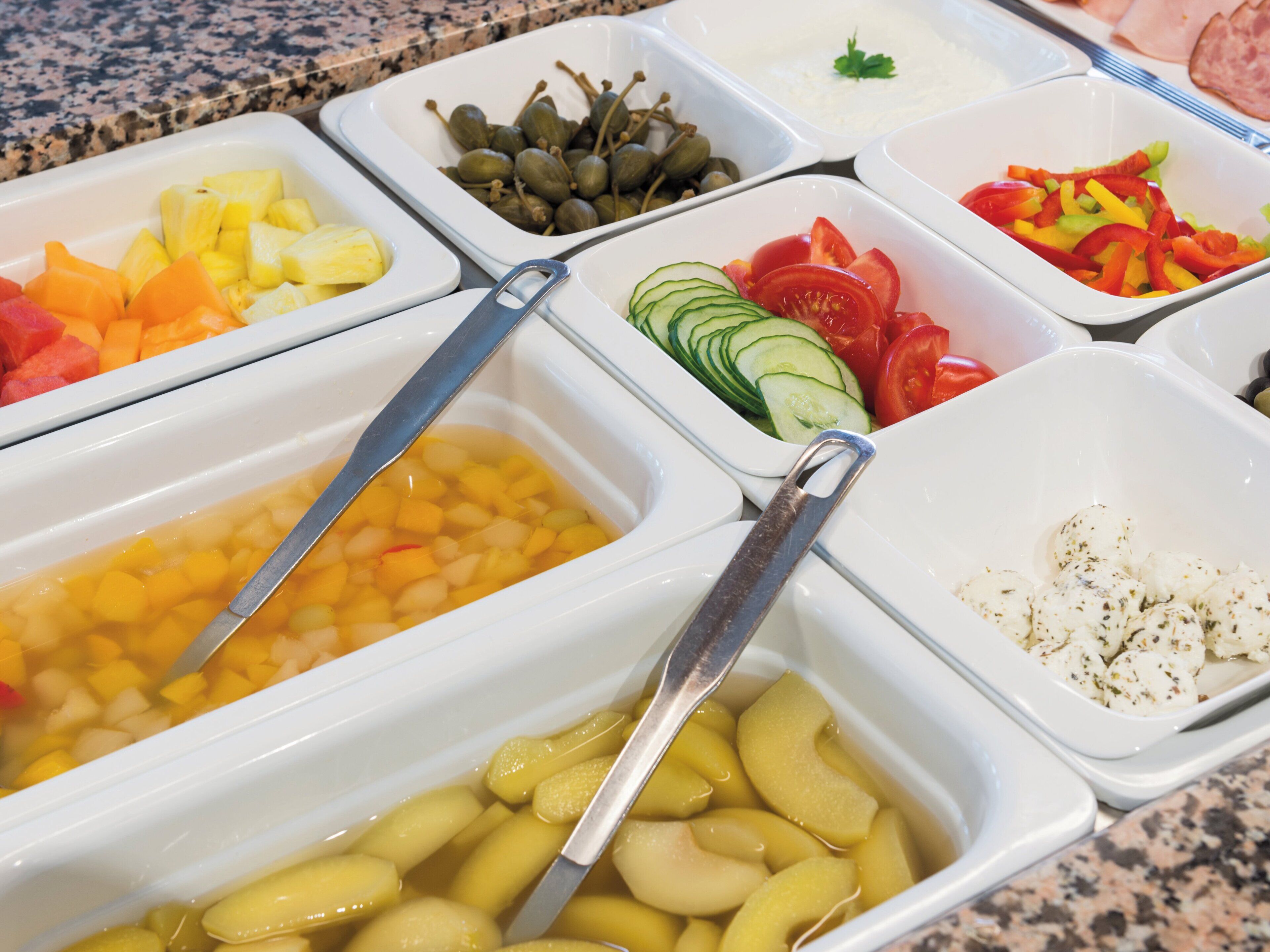 A buffet with various food options including fruits, vegetables, and dips.