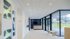 A modern interior with a reception desk, glass walls, and a view of the outdoors. - VitalZeit Hotel Weber (Bad Schönau)
