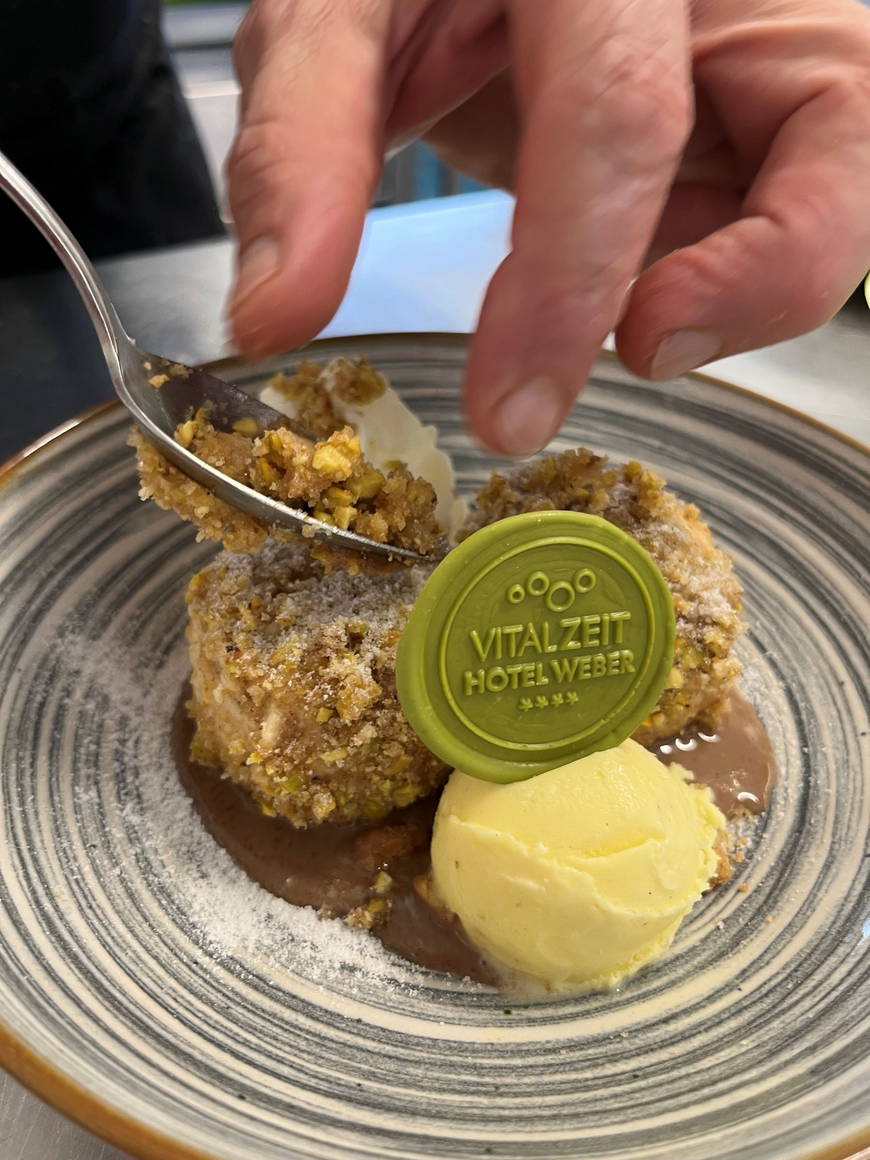 Un dessert composé d’une boule de glace et d’un récipient portant l’inscription « HÔTEL VITALZIT WEBER ».