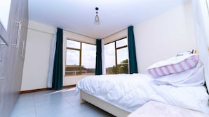 Un dormitorio con cama, ventana y lámpara en el techo.