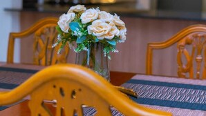 Una mesa de comedor con un jarrón de flores blancas, sillas de madera y un mantel a rayas.