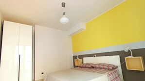 A bedroom with a bed, a wardrobe, a bedside table, and a lamp.