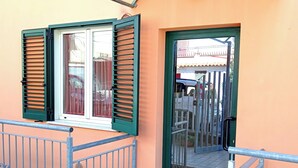 A building entrance with a green door, a window with shutters, and a metal railing.