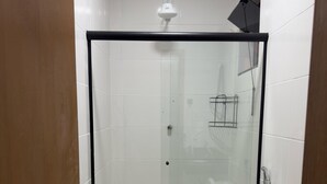Un baño con ducha de vidrio, inodoro y lavamanos.