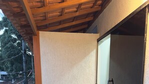 Una terraza de madera con barandilla, puerta de cristal y pared texturizada.