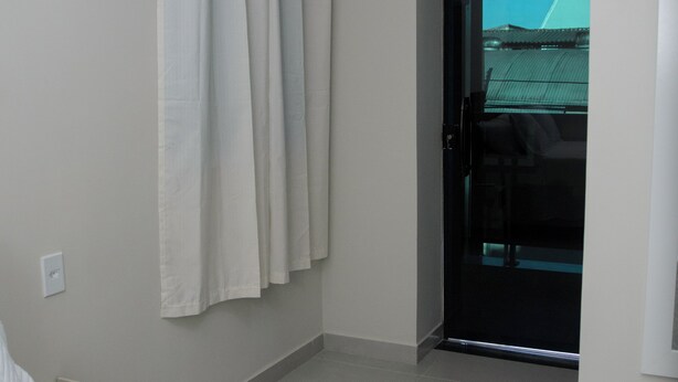 Un dormitorio con una cama, una mesita de noche y vistas al exterior por una puerta.