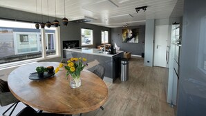 Una cocina moderna con una isla central, un comedor con mesa de madera y un amplio ventanal que proporciona luz natural.