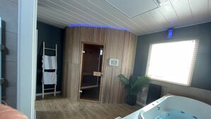 Un cuarto de spa con pared de paneles de madera, una escalera de madera, una bañera grande y una ventana con persianas.