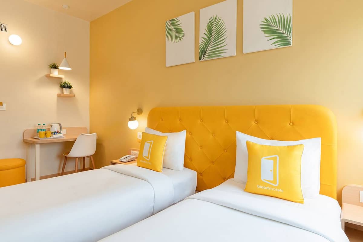 Ett hotellrum med två sängar, ett skrivbord och en stol.