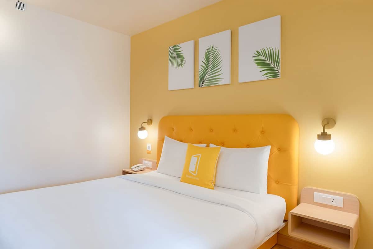 Ett hotellrum med en stor säng, en sänggavel, sängbord och konstverk som hänger på väggen.