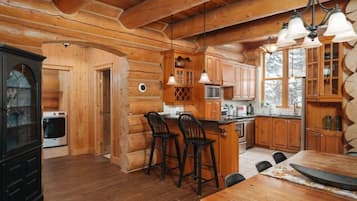 L’intérieur d’une cabane en rondins comprend une table à manger en bois, des tabourets de bar, un coin cuisine avec un four à micro-ondes et un grand placard.
