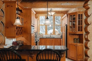 A rustic kitchen with wooden cabinets, a central island, and pendant lighting.