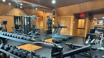 Une salle de sport équipée de divers appareils d’exercice, notamment des tapis de course, des appareils de musculation et des poids libres.
