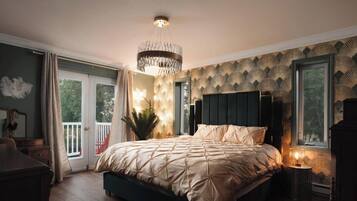 A bedroom with a large bed, a chandelier, a view of the outdoors through a window, and a patterned wall.