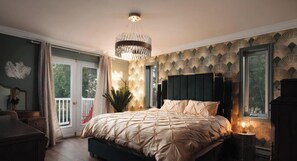 A bedroom with a large bed, a chandelier, a view of the outdoors through a window, and a patterned wall.