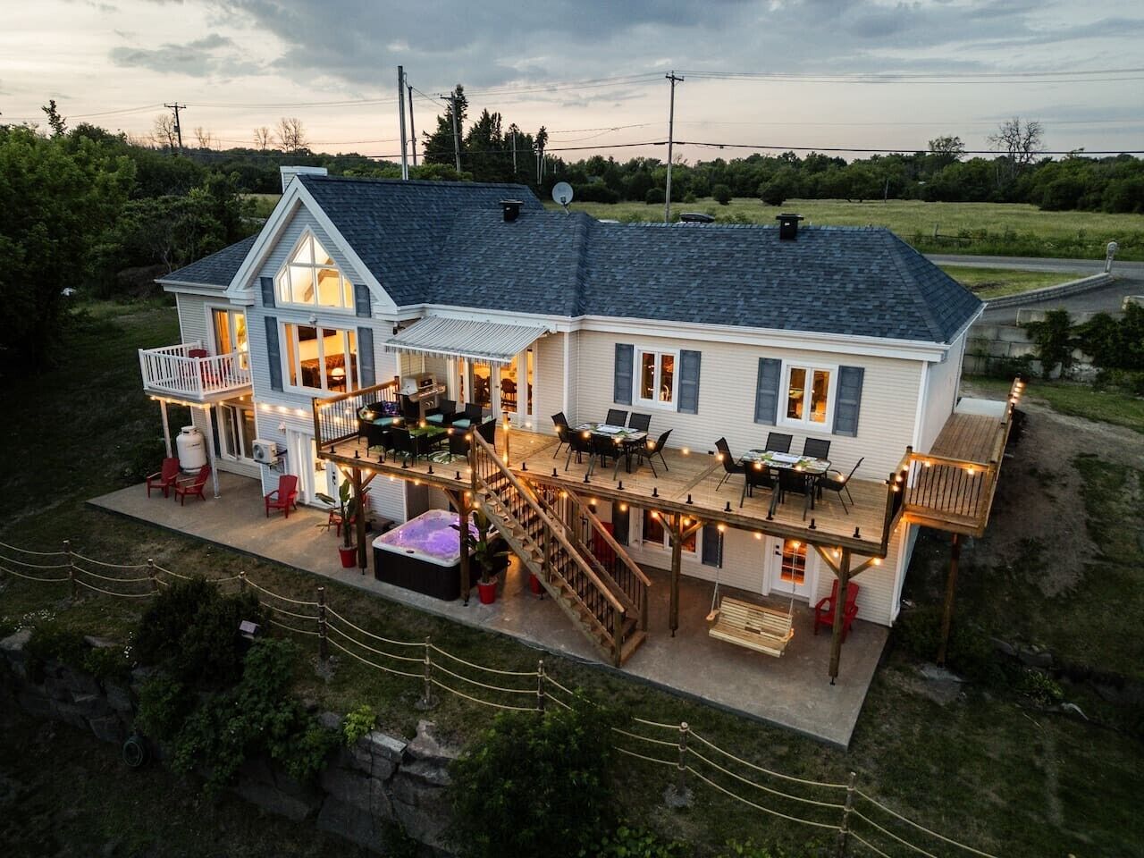 A two-story house with a deck, outdoor seating, and a hot tub.