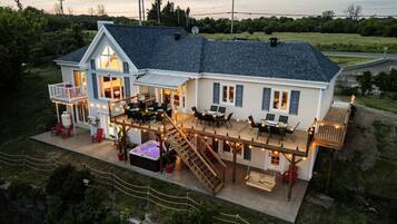 A two-story house with a deck, outdoor seating, and a hot tub.