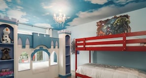 A child's bedroom with a bunk bed, a castle-themed play area, and a superhero mural on the wall.