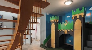 A staircase with wooden balusters and a castle-themed play area with a slide.