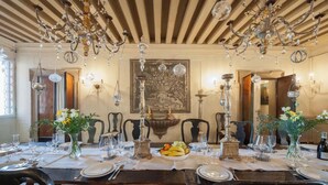 A formal dining room with a long table set for a meal, surrounded by chairs, and adorned with chandeliers and wall-mounted candelabras. - LUXURY GOTHIC PALAZZO - 340 SQM WITH TERRACE A.C, STEPS FROM ARSENALE & BIENNALE (Venice)