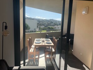 Un balcone con un tavolo apparecchiato per due persone, sedie e vista su una città.