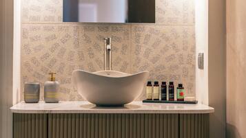 A bathroom with a modern sink, a mirror above it, and toiletries on the counter.
