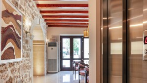 A hallway with stone walls, a modern air conditioning unit, and a door leading to an outdoor area. - La Montre Luxury Suites (Rethymno)