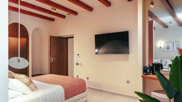 Quarto moderno com cama, vigas de madeira, TV e cafeteira.