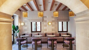 A modern lounge area with a stone archway, cushioned seating, and pendant lighting. - La Montre Luxury Suites (Rethymno)