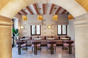 Un área de estar moderna con un arco de piedra, asientos acolchados e iluminación colgante.