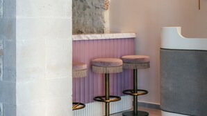 A modern interior with a stone archway, a bar area with stools, and a light fixture. - La Montre Luxury Suites (Rethymno)