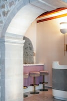 Un interior moderno con un arco de piedra, una zona de bar con taburetes y una lámpara.