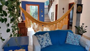 Una sala de estar con un sofá azul, una hamaca y una planta en maceta.