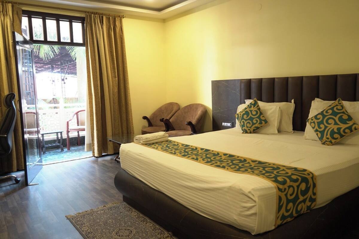 Habitación de hotel con una cama grande, cabecera y vistas al exterior a través de una puerta de cristal.