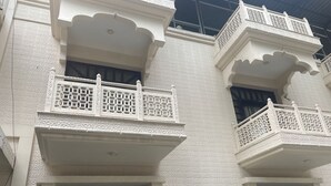 A building with white textured walls, black-framed windows, and ornate balconies with lattice railings. - Hotel Tourist Inn By Sagar (Jalpaiguri)