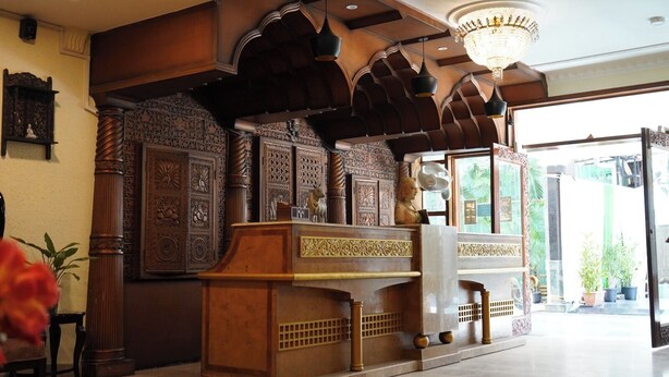 A lobby with ornate wooden paneling, a chandelier, and a reception desk. - Hotel Tourist Inn By Sagar (Jalpaiguri)