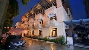A multi-story hotel with balconies, a covered entrance, and a parked car. - Hotel Tourist Inn By Sagar (Jalpaiguri)