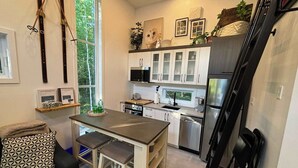 Una cocina moderna con armarios blancos, un refrigerador de acero inoxidable y un ventanal que proporciona luz natural.