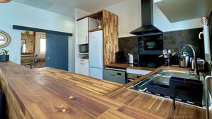 A modern kitchen with a wooden countertop, built-in appliances, and a black range hood.